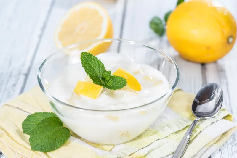fresh made lemon yoghurt decorated with fresh mint on wooden background