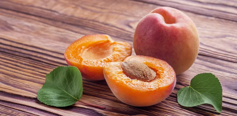 fresh ripe apricots with leaves on a wooden table