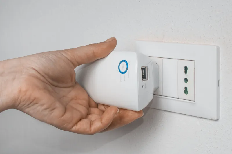 woman plug a wifi repeater on a wall plug