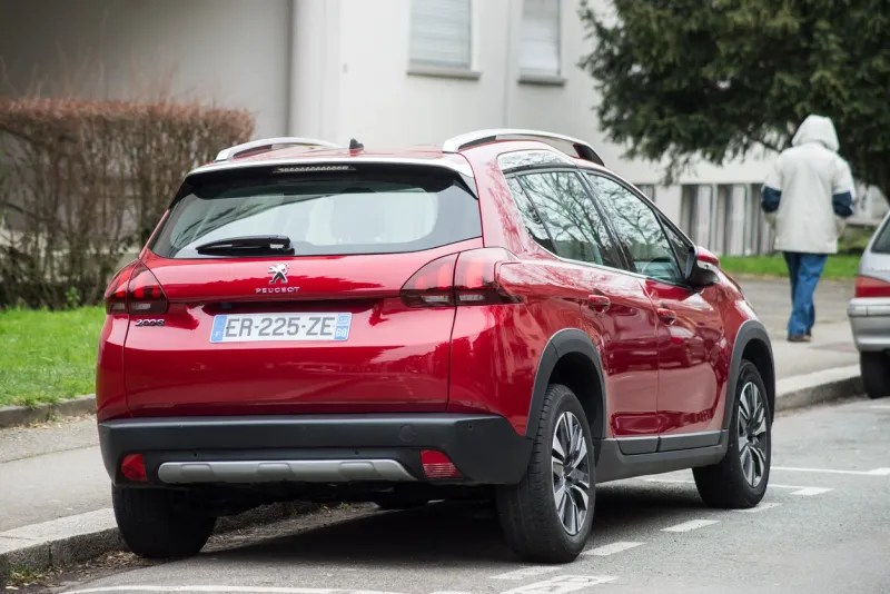 mulhouse - france - 22 march 2021 - rear view of red peugeot 2008, the famous french suv car parked in the street with man on background