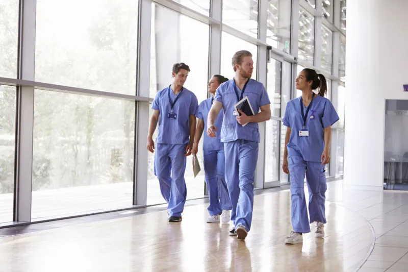 four healthcare workers in scrubs walking in corridor