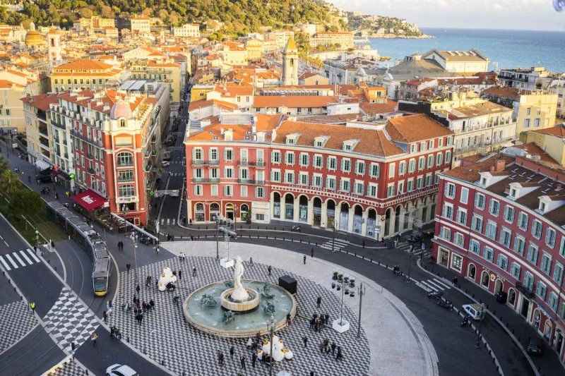 an aerial view of the fontaine du soleil in place messena, nice with the new tram track and buildings of nice and the sea in the background