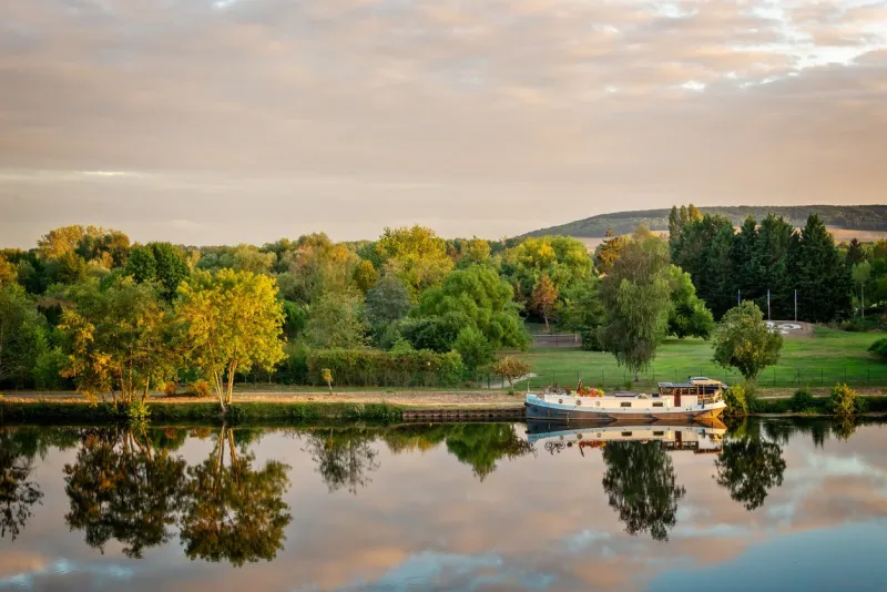 boat on the yonne river with reflections at sunset near joigny in burgundy, france