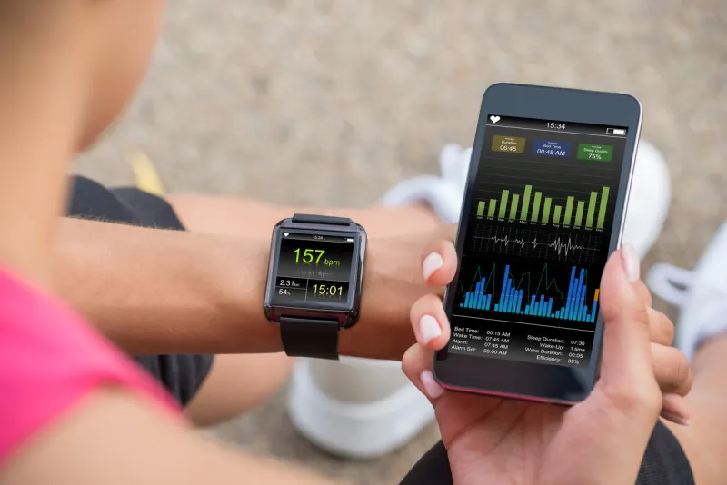 female runner looking at her mobile and smart watch heart rate monitor
