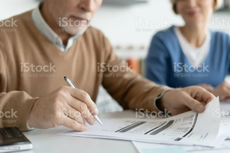 cropped view of mature man holding pen and checking tax form or financial bill family couple calculate profitable investment, social benefits, pension contributions and deposits