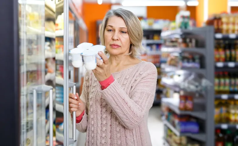 casual adult woman shopping for milk products at supermarket food department
