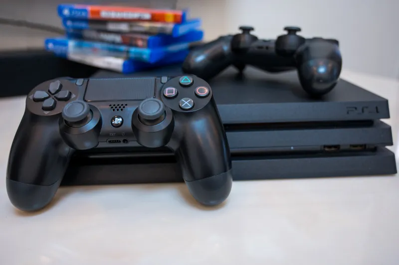 sony play station 4 pro gaming console on the table with two joysticks and some games on dvd for ps4