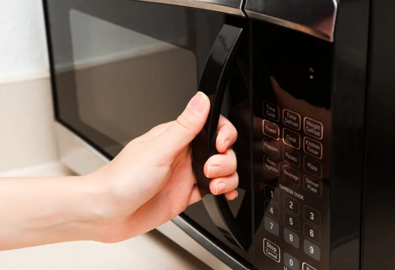 human caucasian hand opening black microwave door indoor household color image in horizontal orientation