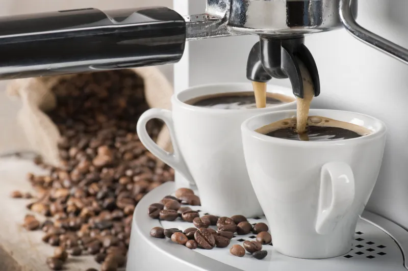 coffee machine makes two coffee with coffee beans on background