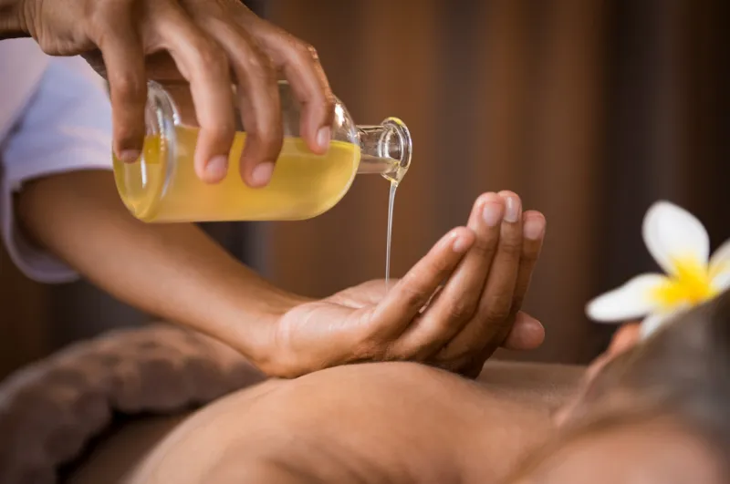 closeup of masseur hands pouring aroma oil on woman back masseuse prepare to do oriental spa procedure for relaxing treatment therapist doing aromatherapy oil massage on woman body