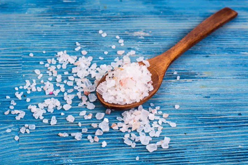 large pink sea salt on blue background studio photo