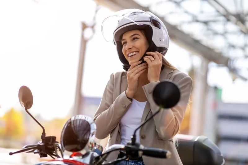woman on scooter tightens helmet