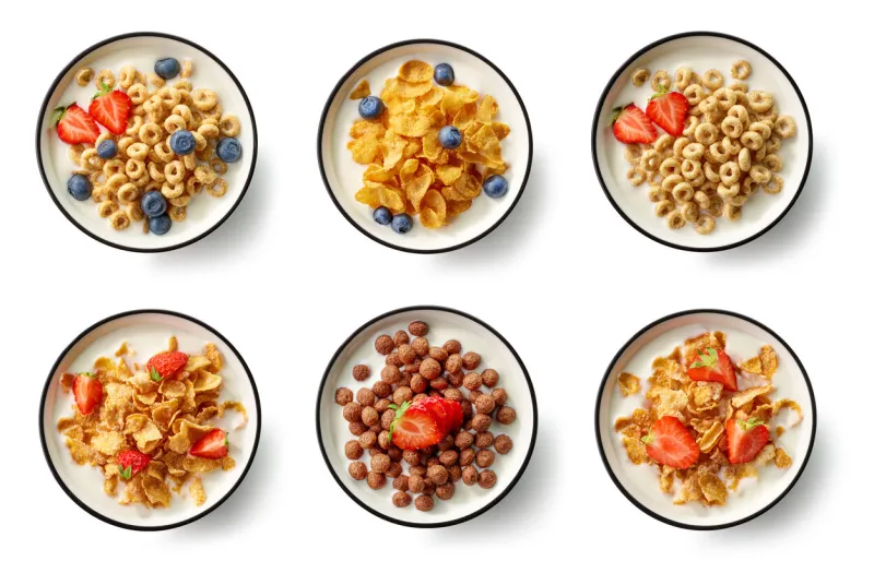 bowls of breakfast cereal with milk and berries isolated on white background, top view