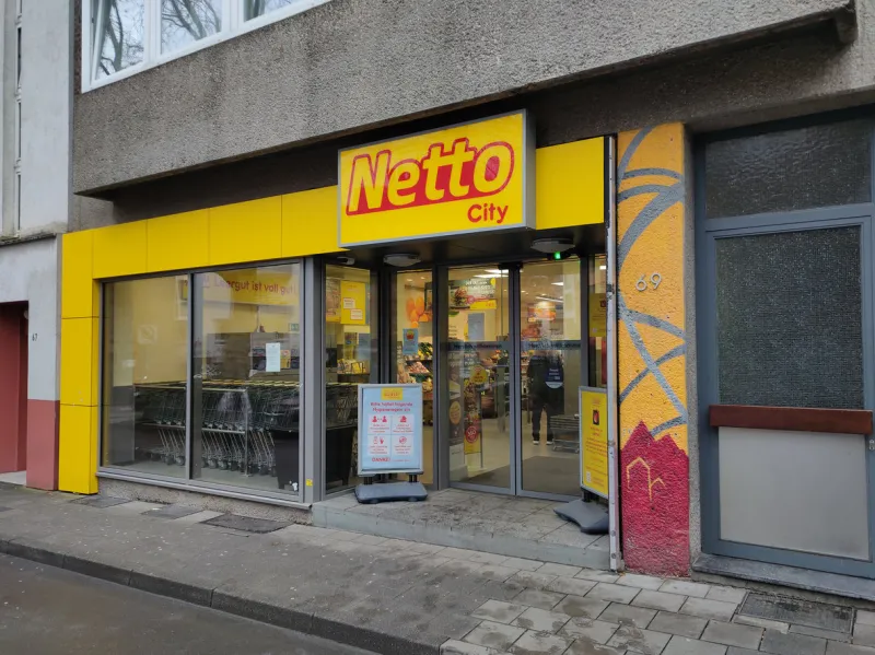 aachen, germany - january 03, 2022    logo and brand name of netto store network with yellow lettering on black background over an entrance to a marketplace store