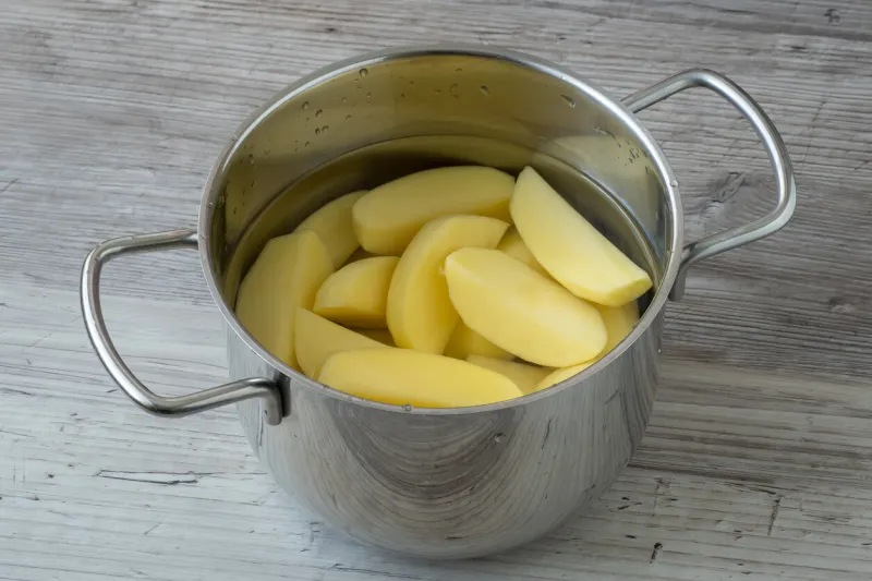 raw peeled potatoes in a pot of water before cooking