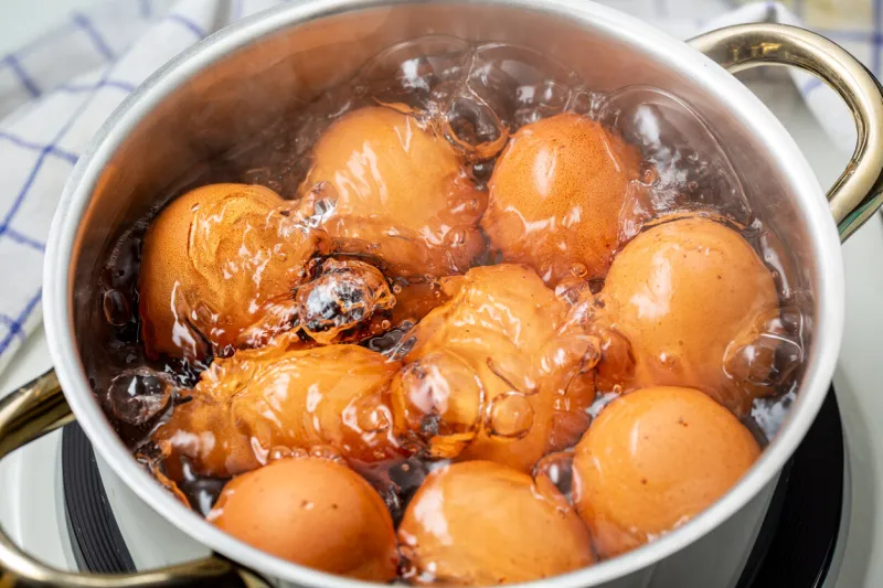 cooking brown chicken eggs in boiling water on electric stove, closeup, elevated view