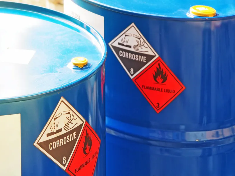 the close-up shot of blue color hazardous dangerous chemical barrels ,have warning labels of corrosive & flammable liquid in daylight on daytime
