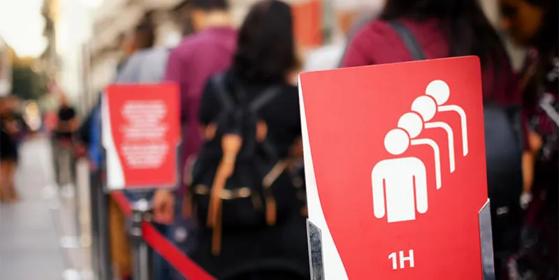 one hour waiting queue at the entrance of a museum with tourists and waiting time signboard