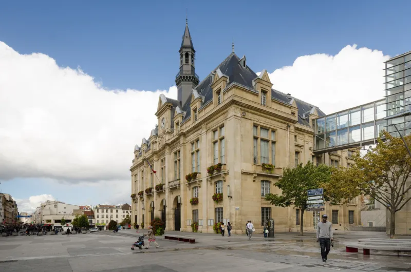 saint-denis, france - september 14, 2015  people are walking in front of the city hall which overlooks place victor hugo with rue de la republique in the distance saint-denis is a suburb of the french capital, paris