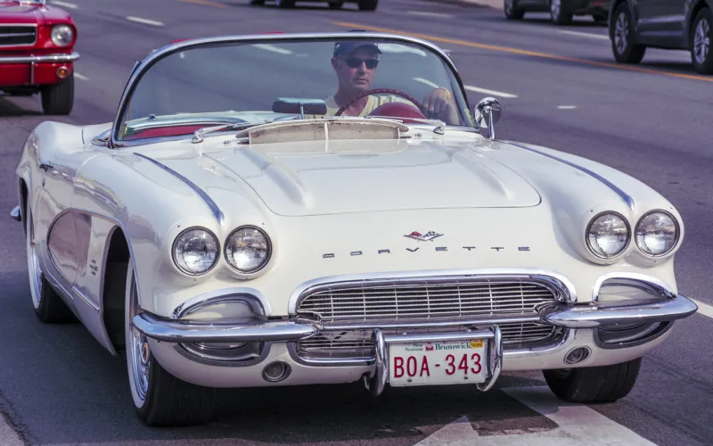 moncton, new brunswick, canada - july 11, 2015   male driver and 1961 chevrolet corvette cruising saturday evening on mountain road during 2015 atlantic nationals automotive extravaganza