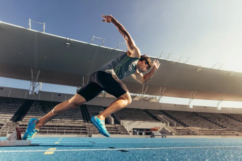 runner using starting block to start his run on running track in a stadium athlete starting his sprint on an all-weather running track