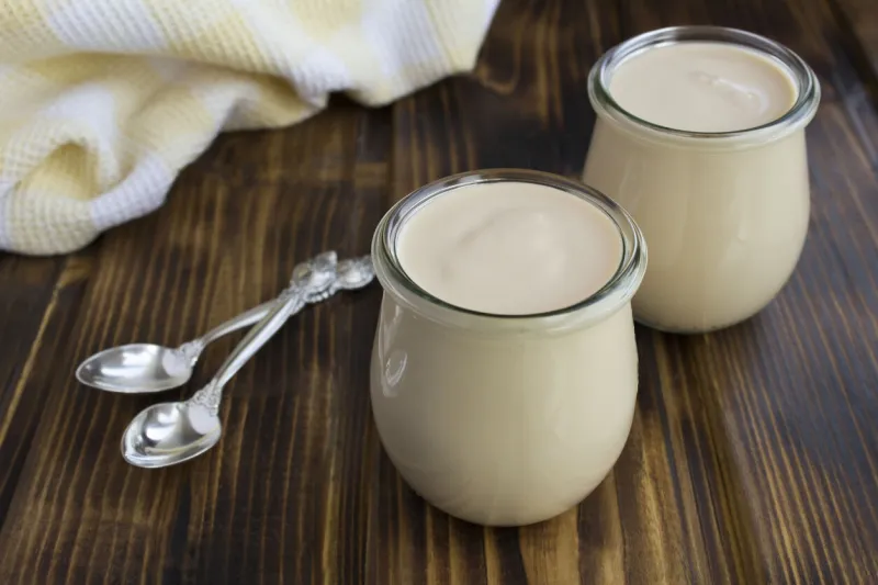 homemade yoghurt in the glass jars on the brown wooden background fermented milk product close-up