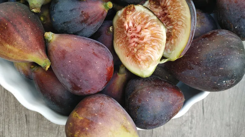 fuente de higos negros frescos sobre mesa de madera rústica