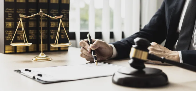 a male lawyer is signing a plea agreement with a client in a fraud case, in which the client has filed a lawsuit against an employee at a company that commits the fraud fraud litigation concept