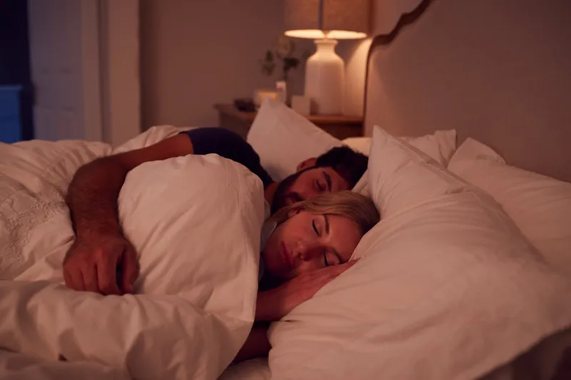 night shot of peaceful couple asleep in bed cuddling together