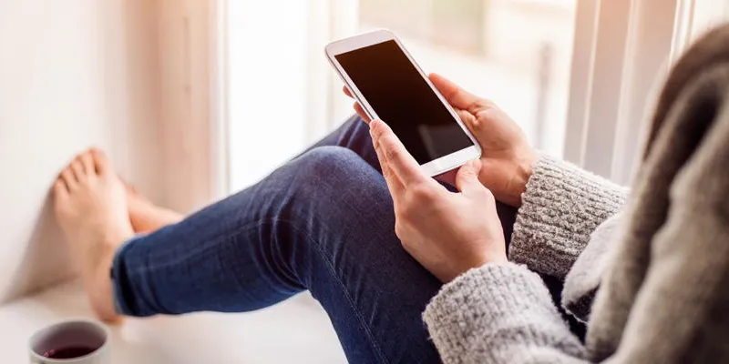 femme méconnaissable assis sur le rebord de la fenêtre avec téléphone intelligent, envoyer des sms