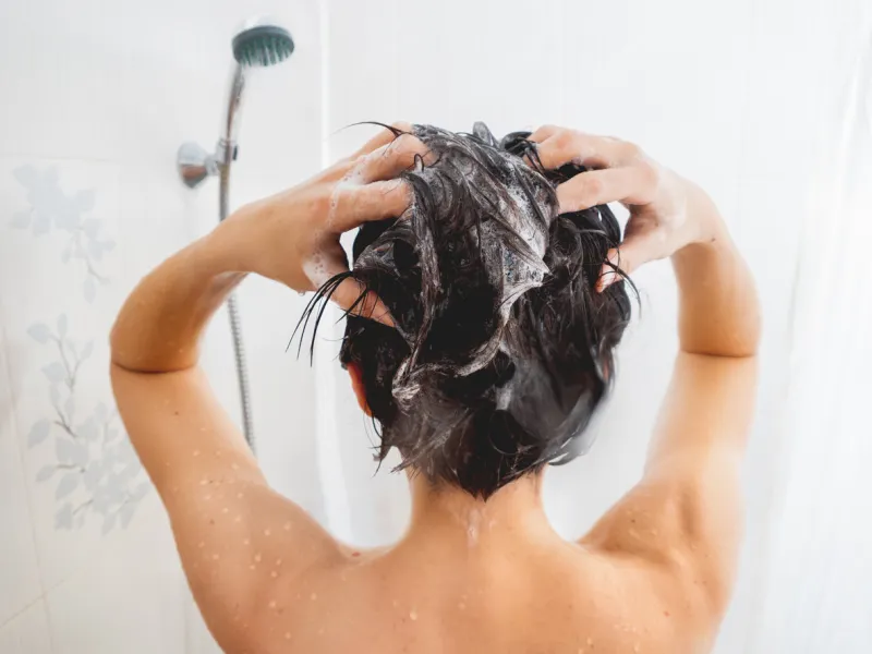 naked woman with short hair takes a shower woman washes her hair with shampoo white bathroom