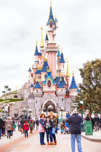 paris, france - january 12, 2015  happy people (family, child) near famous castle in the disneyland paris are taking photo disneyland is one of the most popular destinations in paris travel (vacation), entertainment, childhood concept france europe