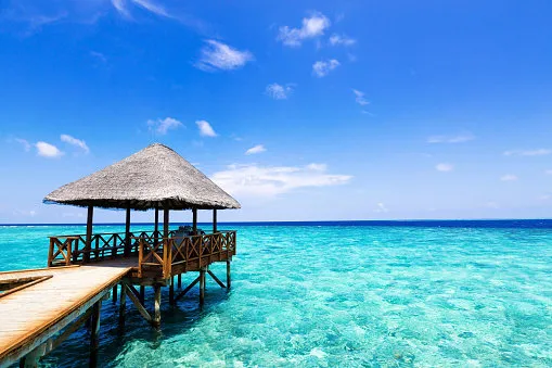 tropical travel card with pristine beach and water bungalows at maldivian island
