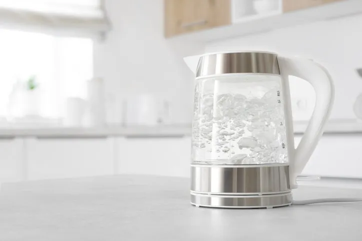 modern glass electric kettle boiling on kitchen table