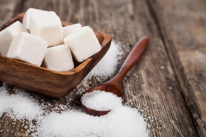 bowl with sugar and a wooden spoon on an old wooden background