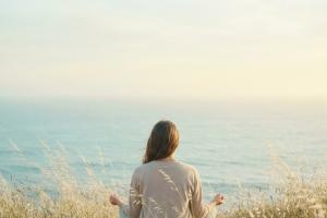 Une personne, vue en plan moyen dans une clairière côtière calme et baignée de soleil, contemple l'o