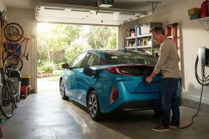un voiture hybride dans le garage d'une maison. On voit un utilisateur en train de la brancher sur l