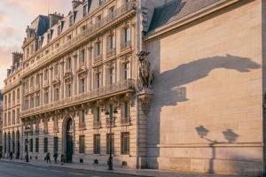Prompt 3: A wide shot of a grand, Haussmannian-style building facade in Paris, bathed in the soft, w