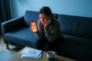 A cinematic, high-quality photo of a young adult (20s) sitting on a minimalist sofa, looking stresse