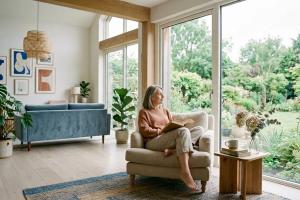 Un salon spacieux et aéré aux larges baies vitrées laissant entrer une lumière diffuse. Une personne