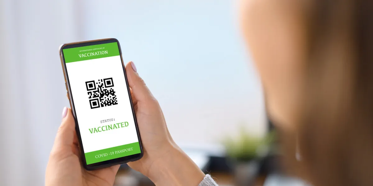 the smartphone screen with an international covid passport in hand of a woman, coronavirus vaccination confirmation, display of mobile phone with an approved necessary vaccine certificate for travel