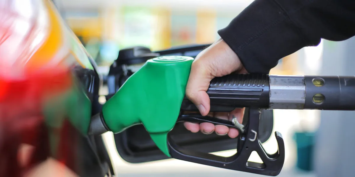close up hand holding green gasoline fuel nozzle and being fill gas tank of black car in gas station concept of global fossil fuel consumption replace by alternative energy in near the near future