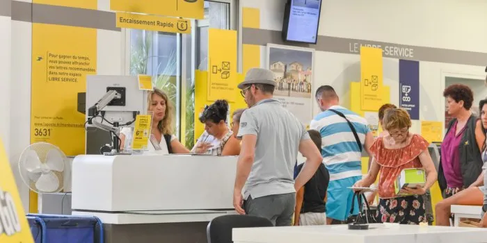cap d'agde, france - july 27, 2016  people stand in a queue for post office services sending parcelcardboard boxes