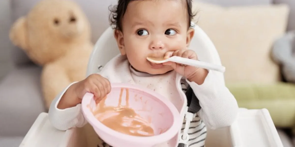 shot of a baby eating a meal at home