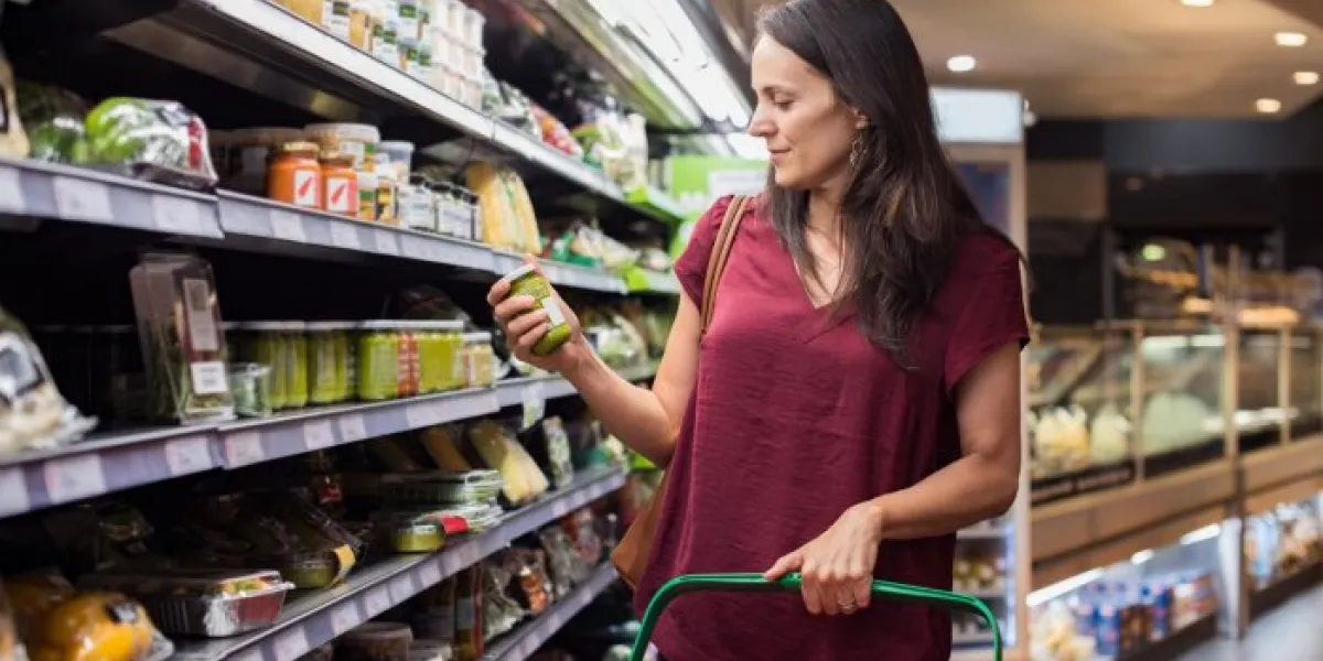 young woman shopping in grocery store mature woman checking food label in supermarket latin woman holding shopping basket and choose a product in supermarket