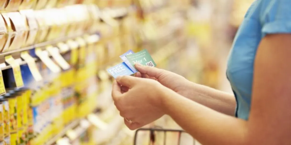 woman in grocery aisle of supermarket with coupons