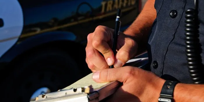 a police office on the side of the road as he writes a ticket