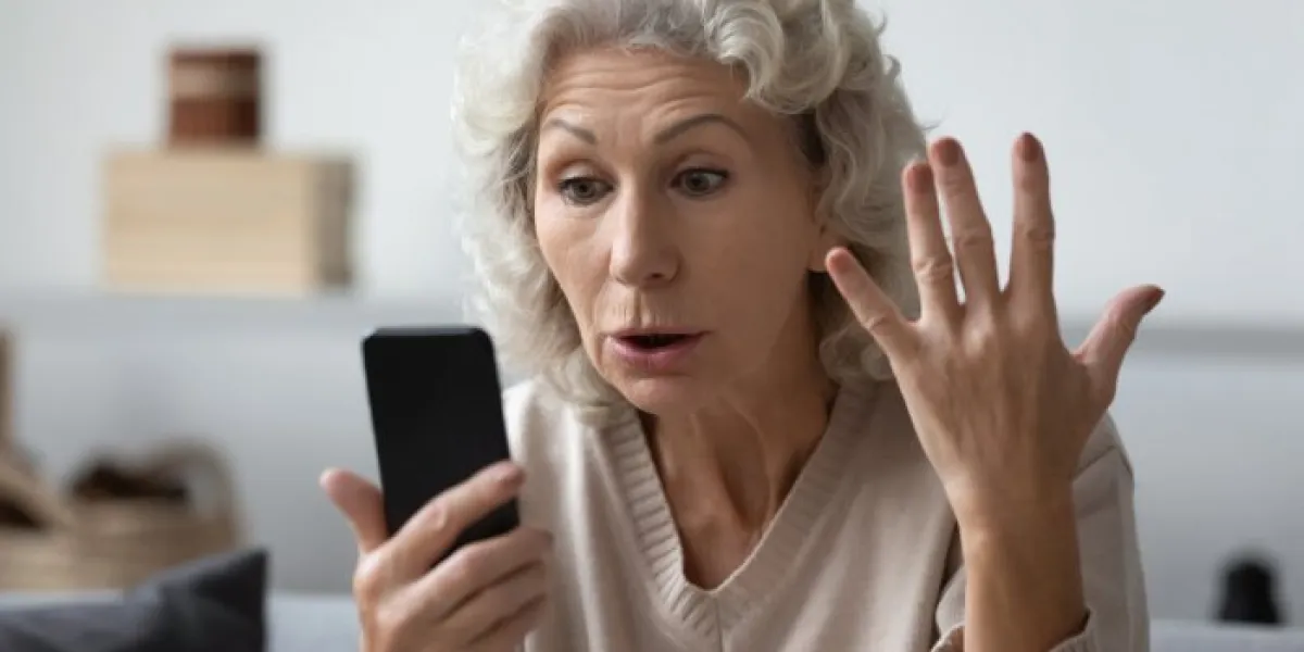angry shocked mature phone user staring at screen in surprise elderly lady worried about app error, data stealing, scam, bad news, problems with smartphone annoyed woman using cell for video call