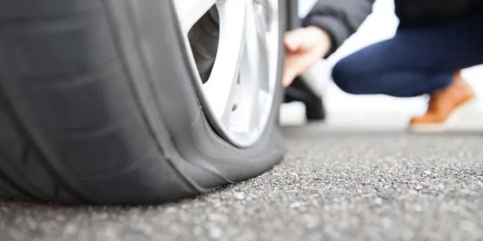 man touching a flat tire on the roadside