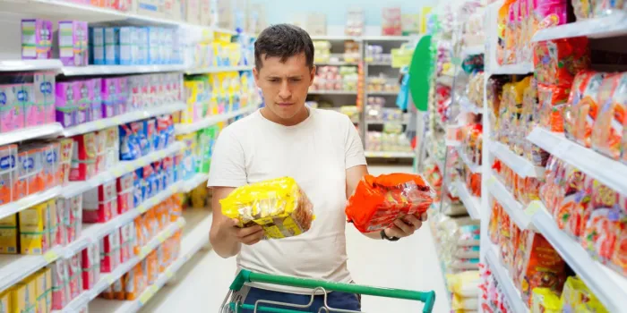 young caucasian man make choose between two similar goods shopping in supermarket or grocery